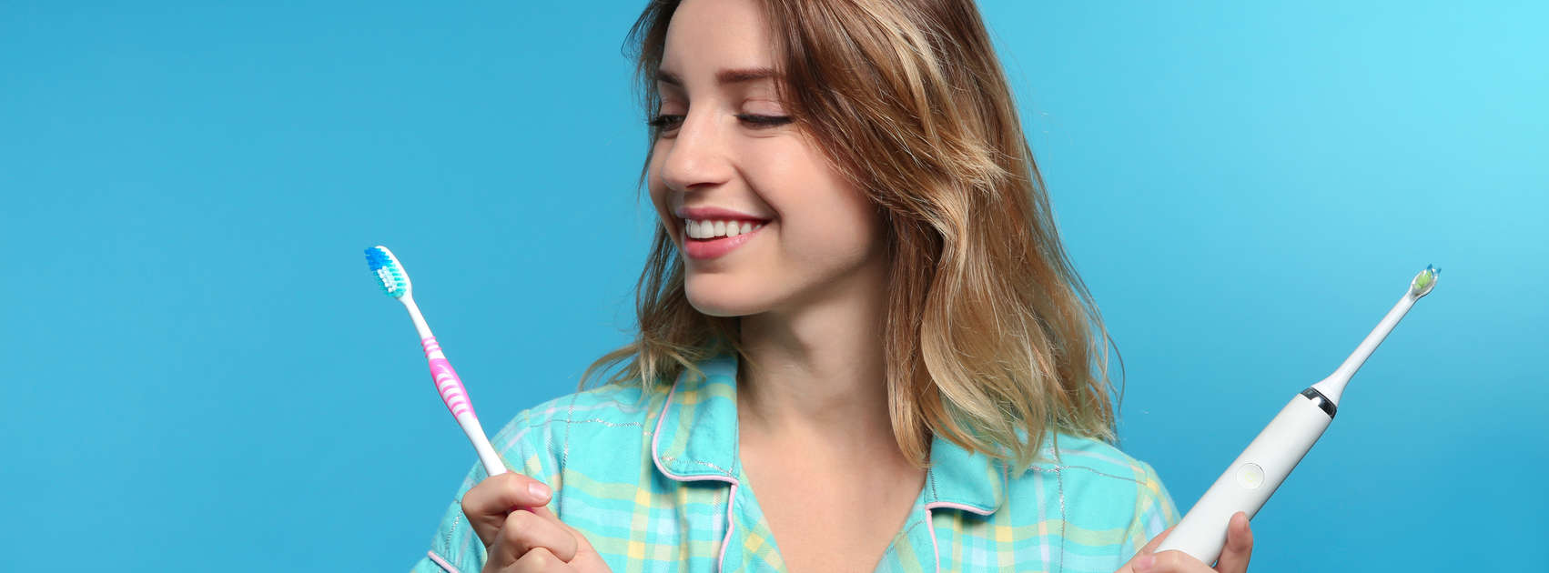 Jonge vrouw kiezen tussen handmatige en elektrische tandenborstels op kleur achtergrond