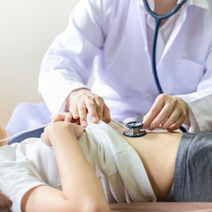 un médecin examine l'estomac de l'enfant avec un stéthoscope