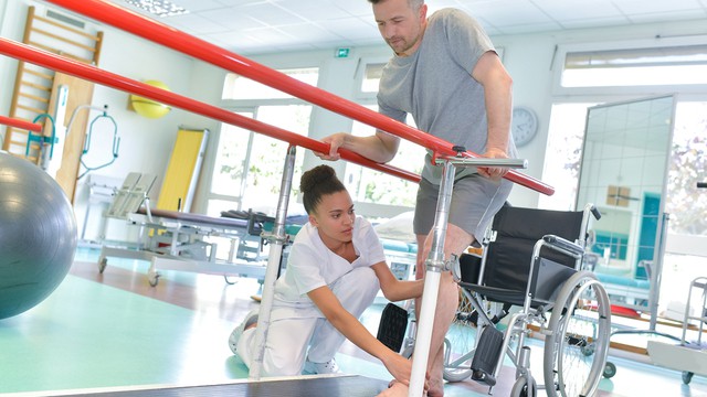 Un ergothérapeute aide un patient à marcher